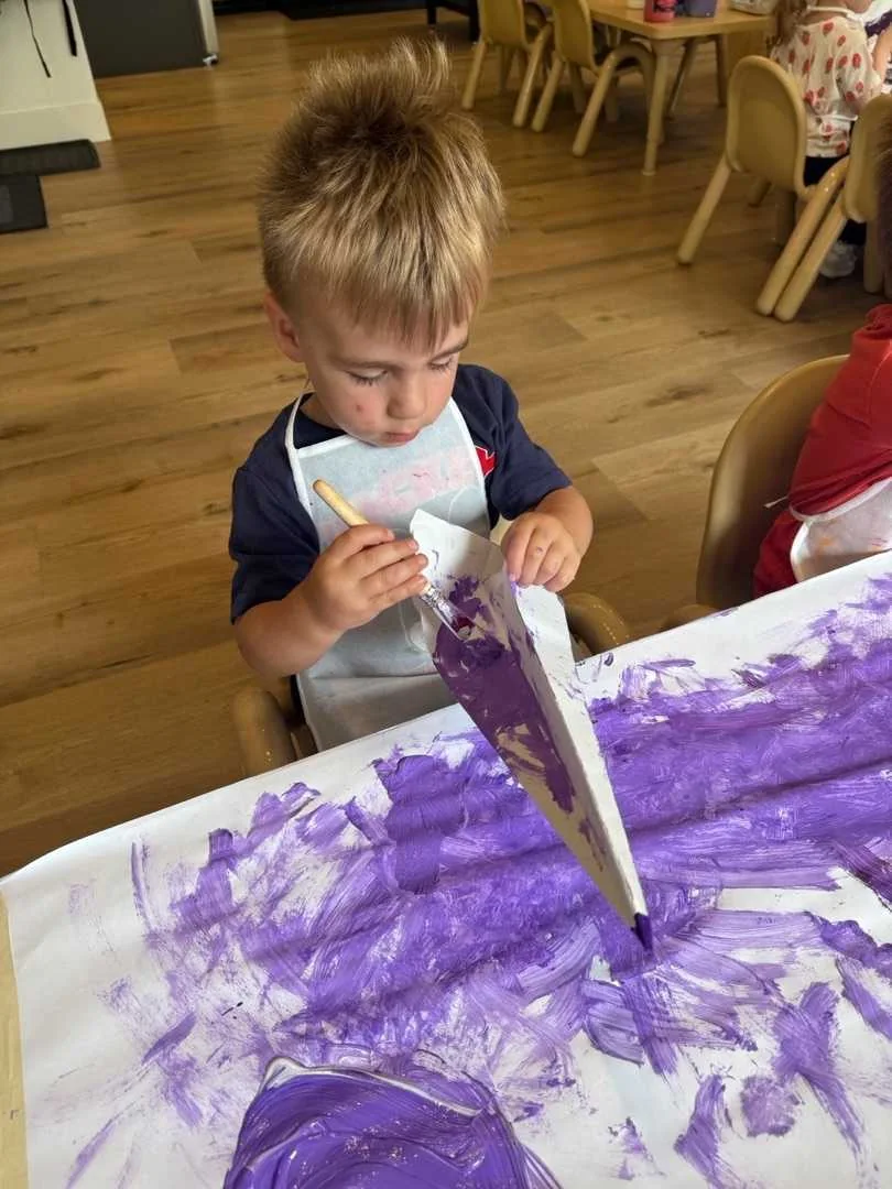 UMC Preschool child focused on a purple painting activity