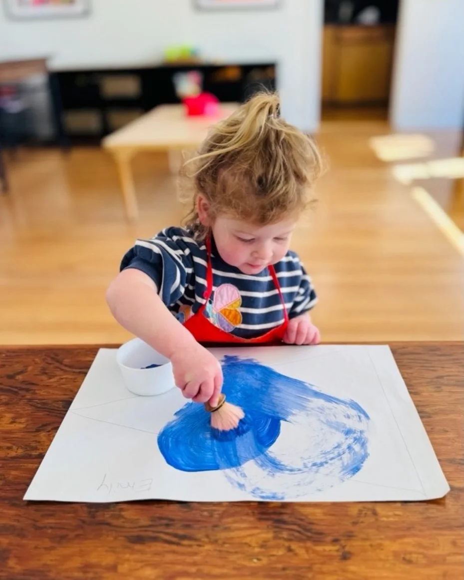 A UMC Preschool child focused on a painting activity
